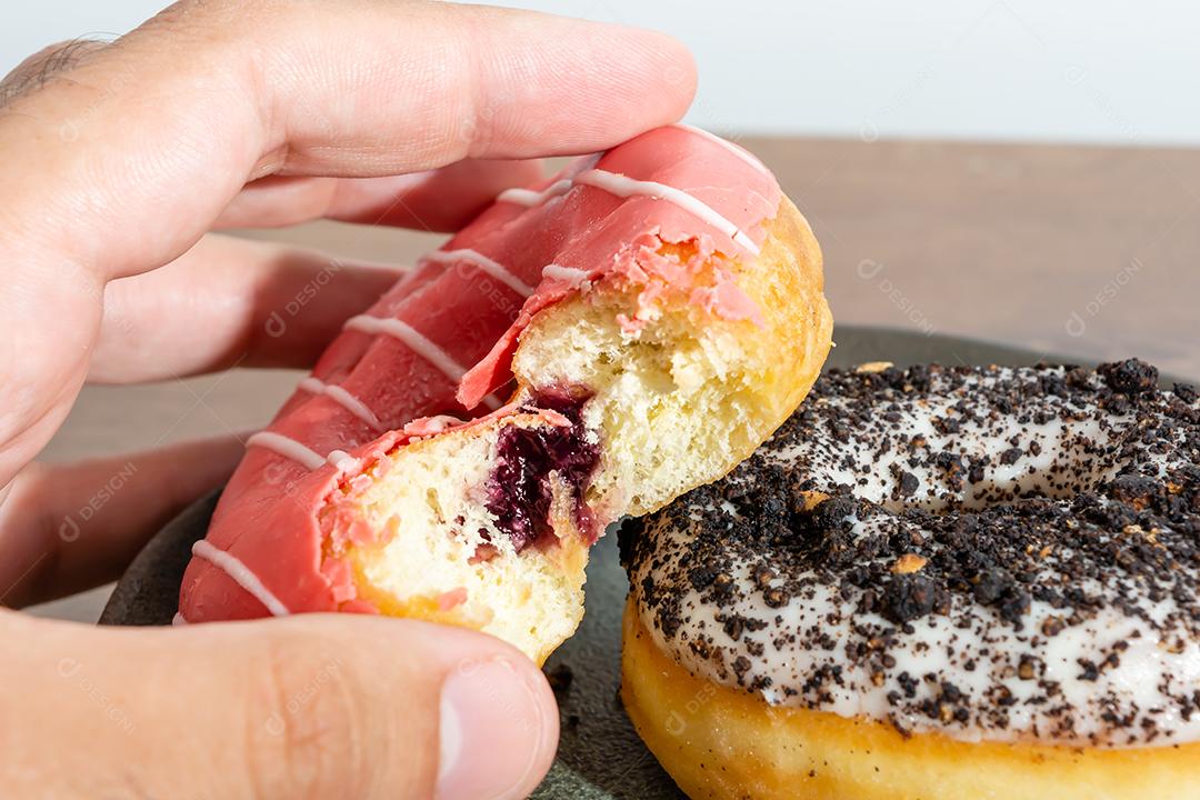 Male hand holding everglazed donuts over wooden table white background