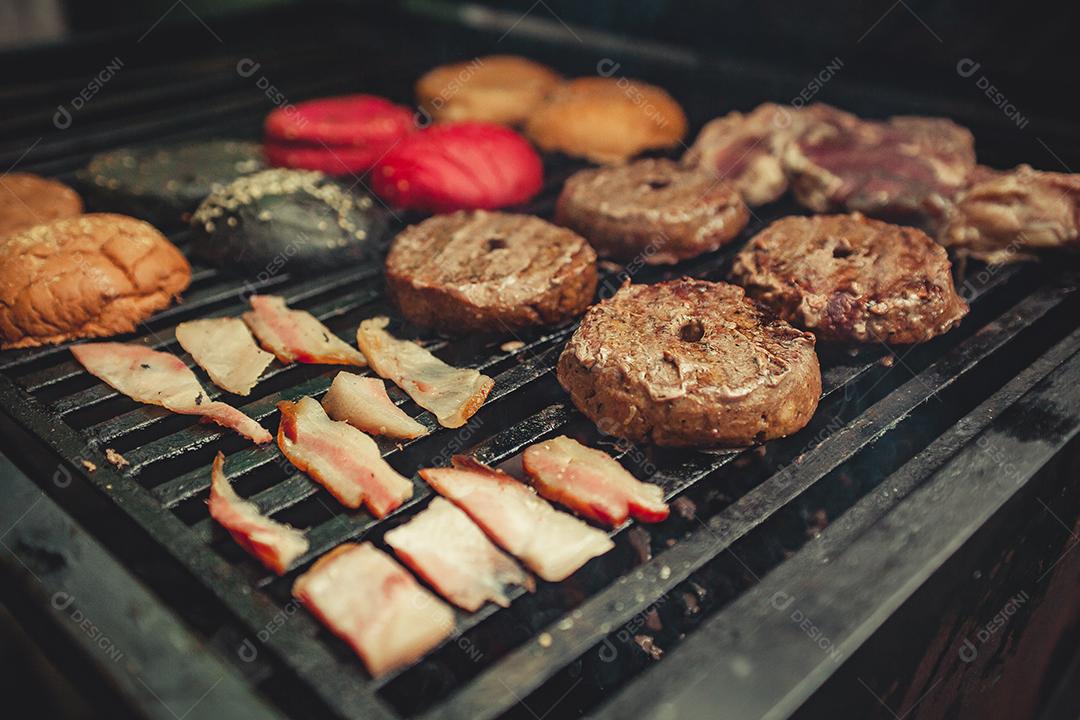 Chapa quente com hambúrguer, bacon  e pães em preparação