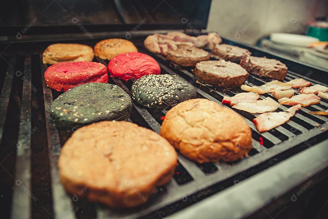 Chapa quente com hambúrguer, bacon e pães em preparação