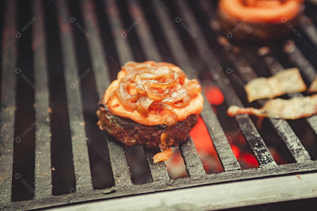 Chapa quente com hambúrguer, cebola e pães em preparação