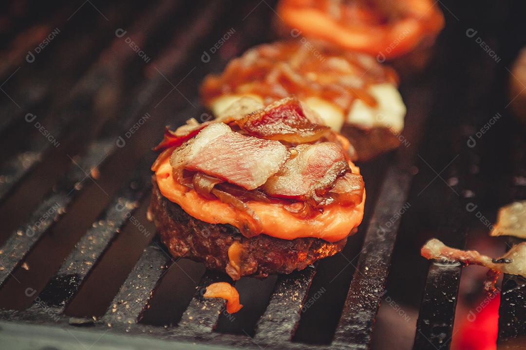 Chapa quente com hambúrguer, cebola e pães em preparação