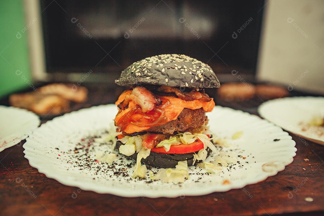 Prato branco com hambúrguer com pão da cor preta