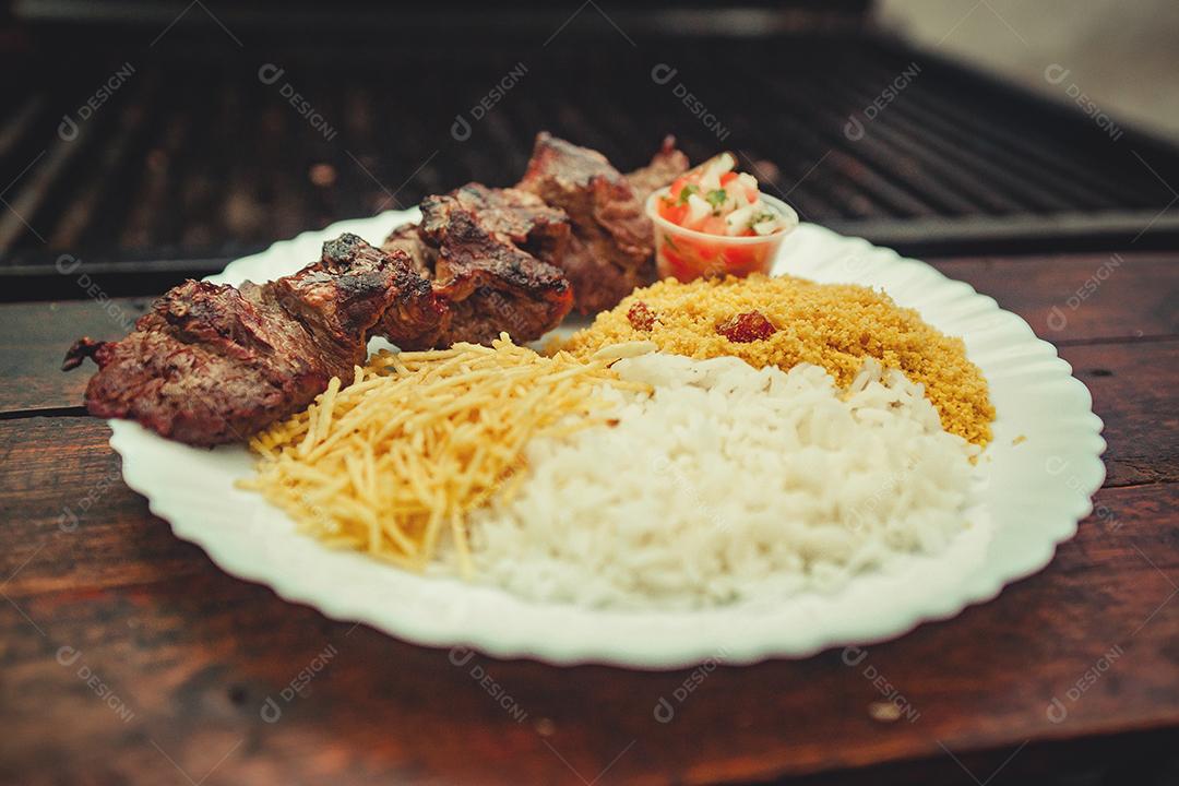 Prato de comida acompanhado de espetinho de carne bovina