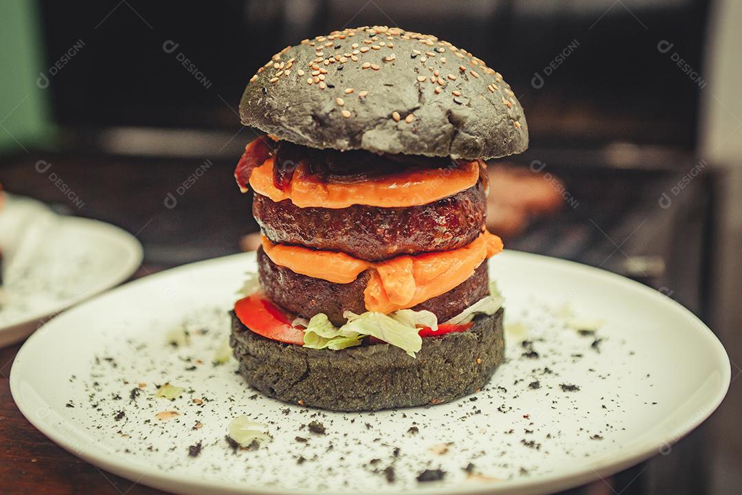 Prato branco com hambúrguer com pão da cor preta