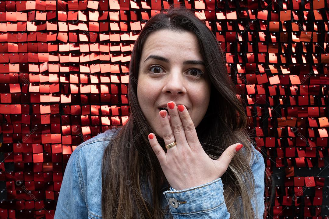 Mulher espantada com a mão na boca em um vermelho texturizado