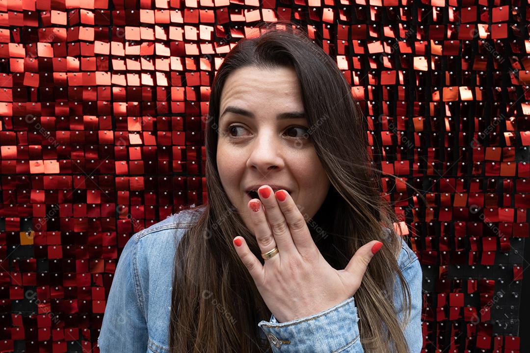 Mulher espantada olhando para o lado com a mão na boca em brilhante re