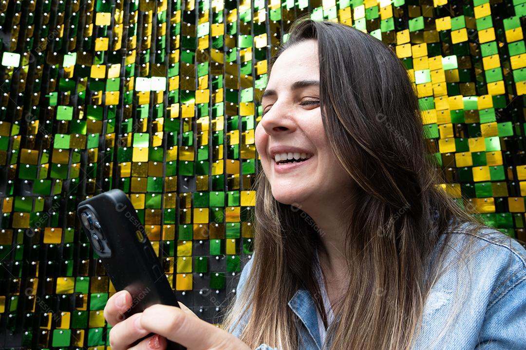 Mulher usando telefone celular e sorrindo em fundo azul brilhante