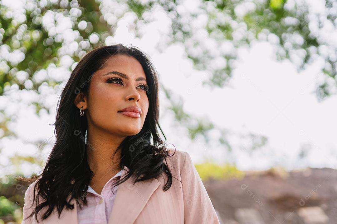 Retrato de uma mulher latina atraente andando no parque no outono em um dia ensolarado e sorrindo.