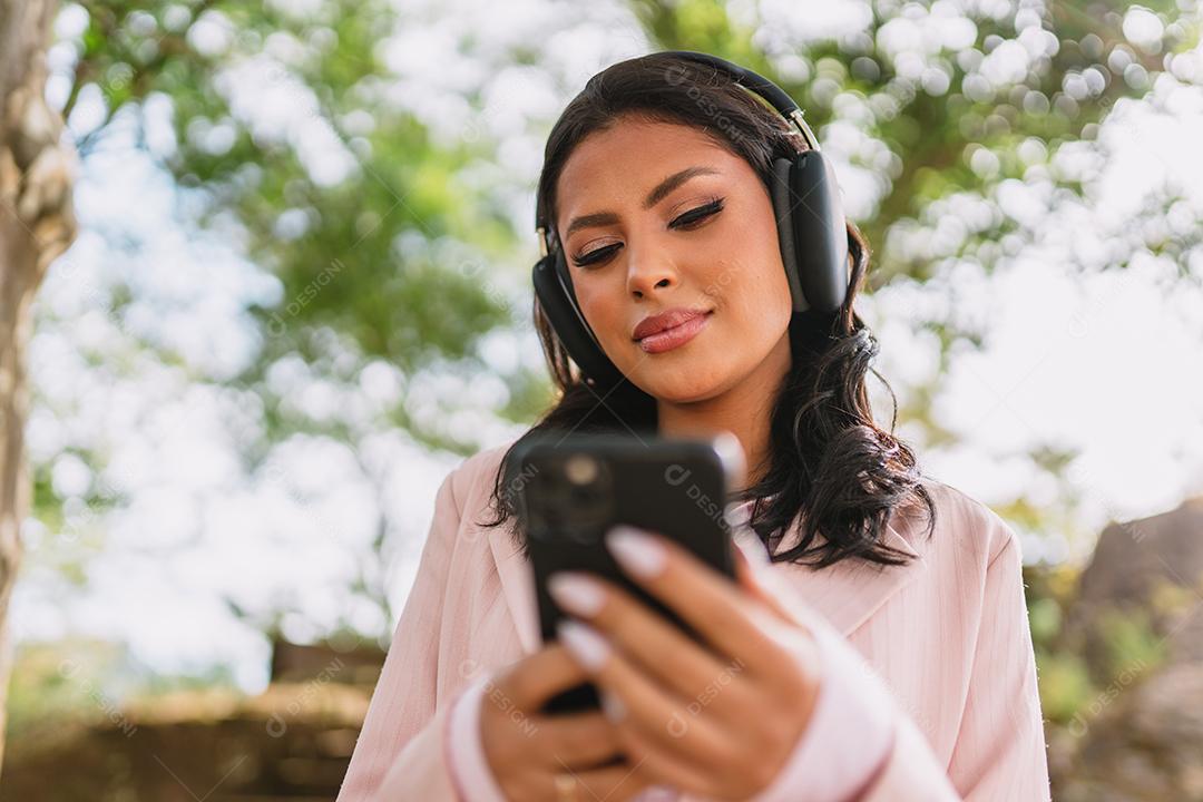 Mulher jovem e bonita Latina usando smartphone em pé na rua da cidade. Retrato de mulher latina sorridente usando telefone celular.