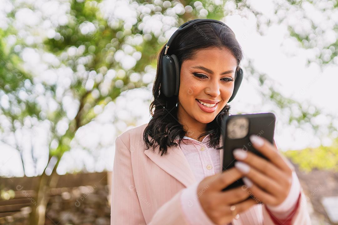 Mulher jovem e bonita Latina usando smartphone em pé na rua da cidade. Retrato de mulher latina sorridente usando telefone celular.