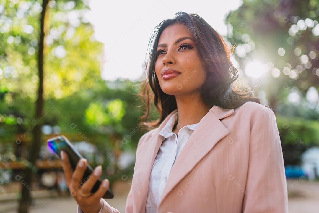 Retrato de uma mulher latina atraente andando no parque no outono em um dia ensolarado e sorrindo