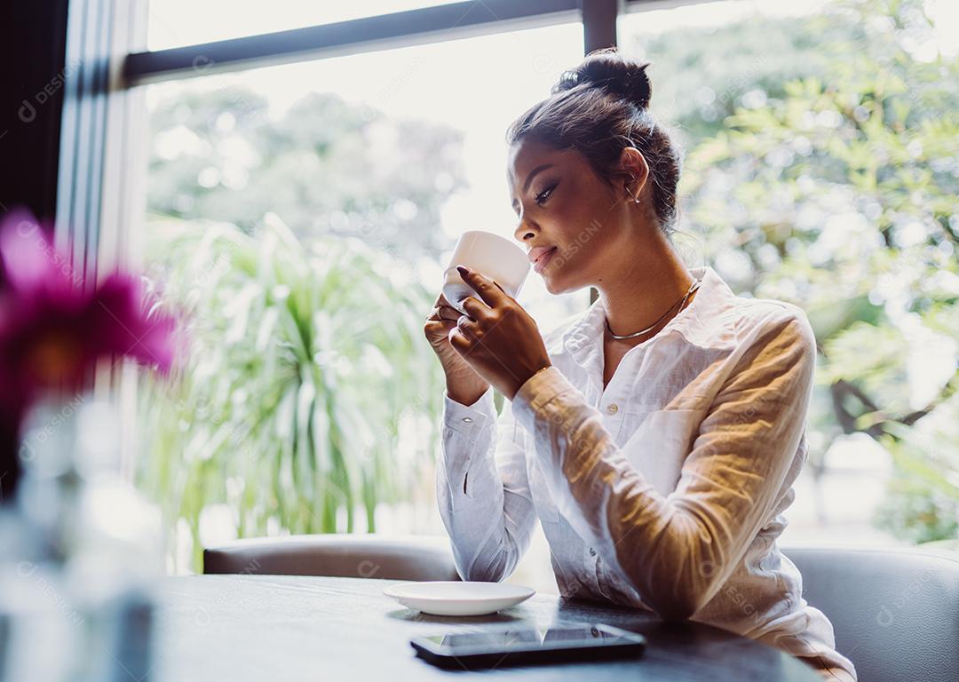 Mulher latina em um café bebendo café.