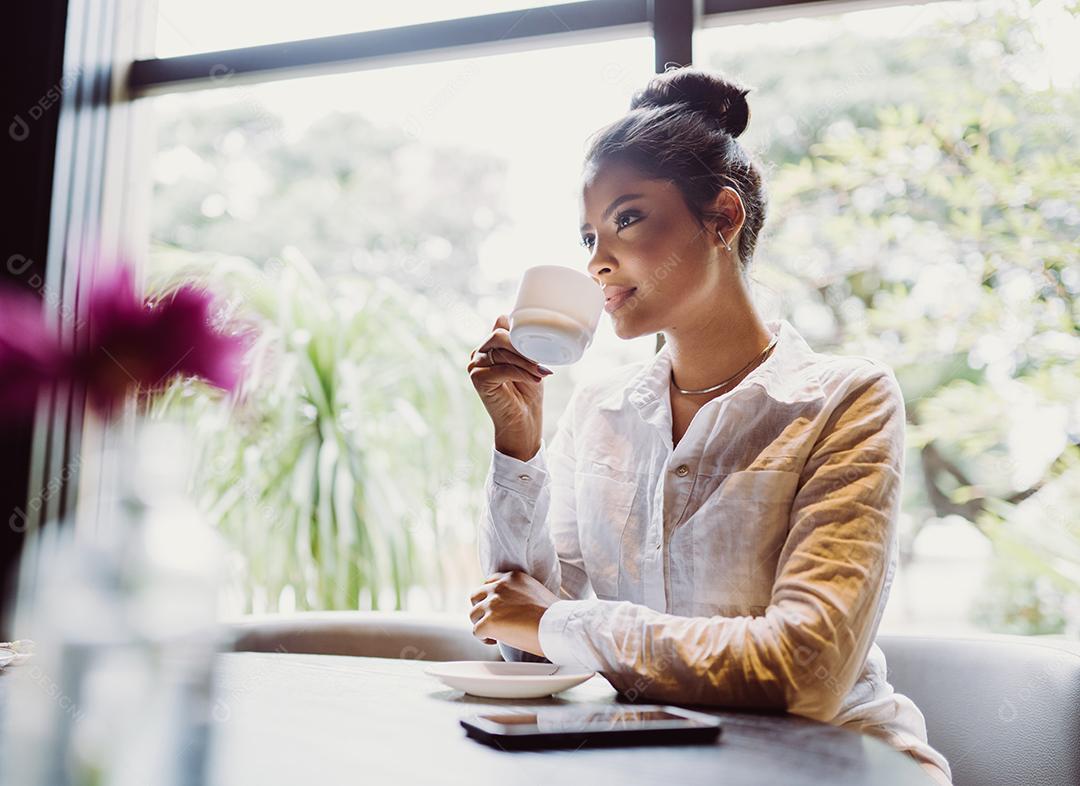 Mulher latina em um café bebendo café.