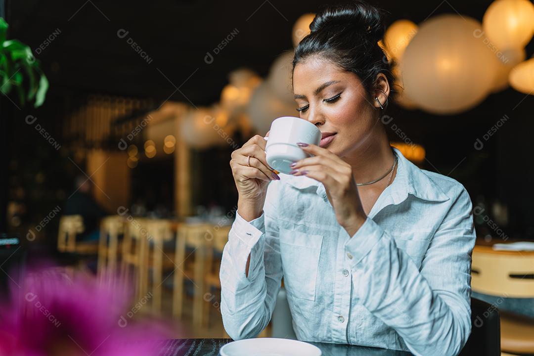 Mulher latina em um café bebendo café.