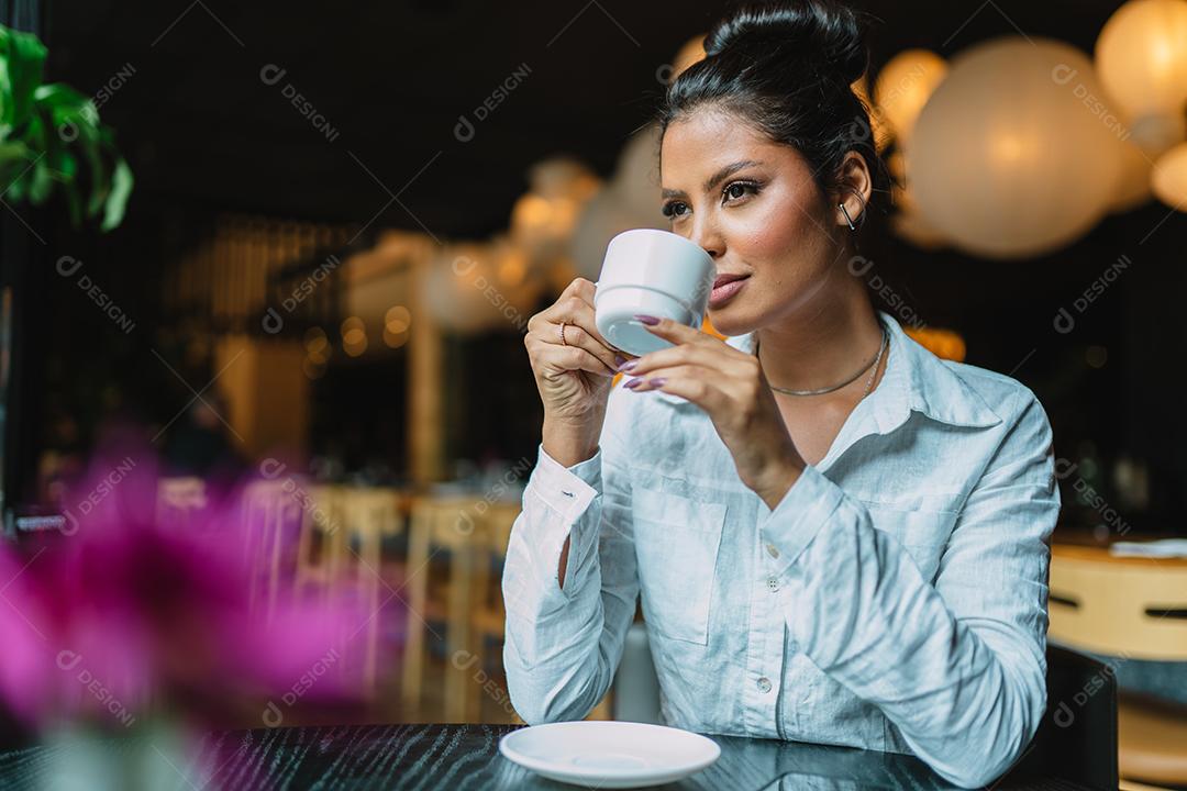 Mulher latina em um café bebendo café.