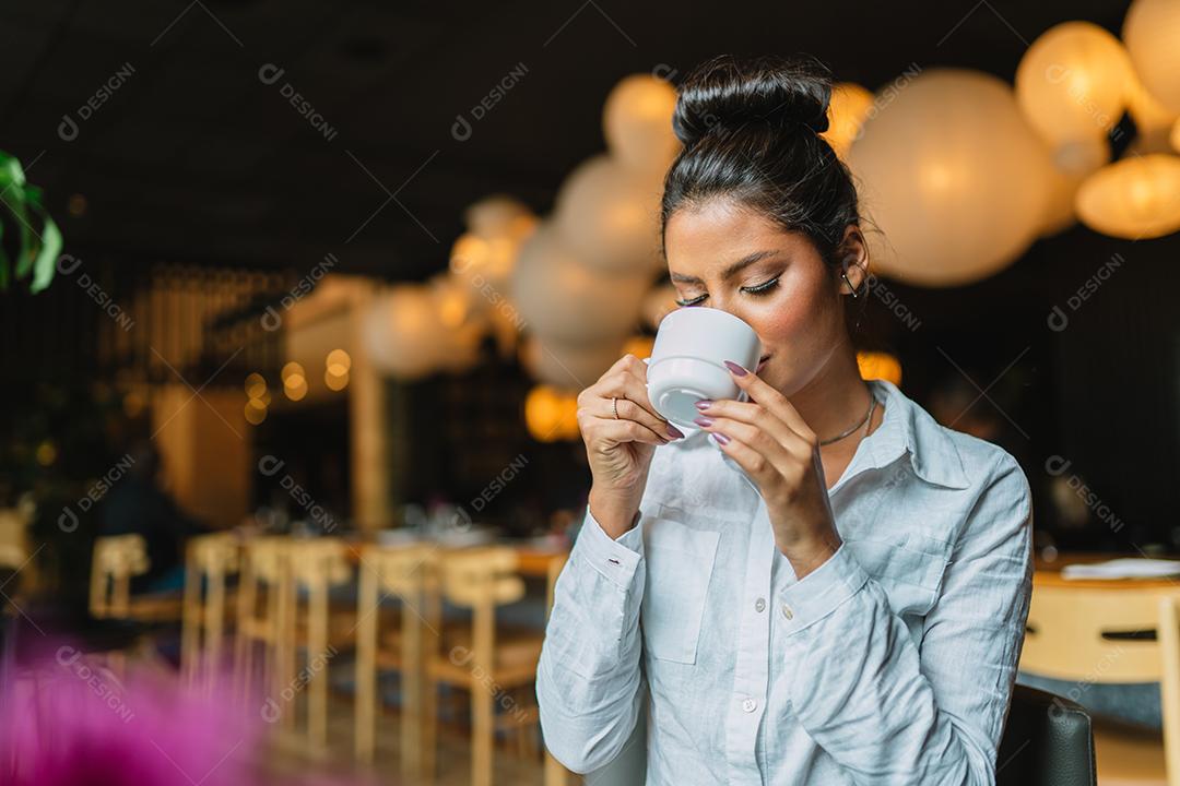 Mulher latina em um café bebendo café.