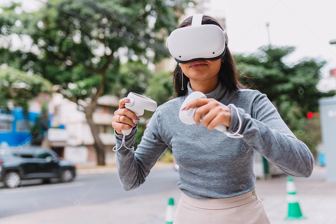 Jovem latina em pé com óculos de realidade virtual e mantenha joysticks ou dedo como uma arma.