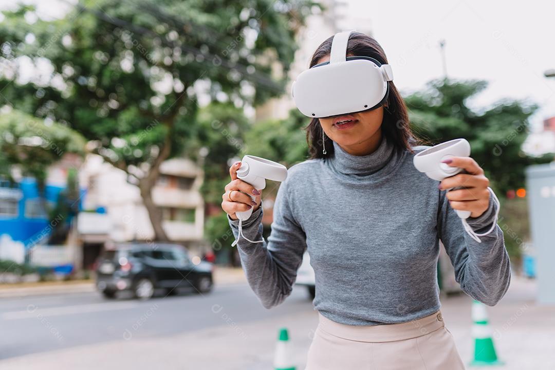 Jovem latina em pé com óculos de realidade virtual e mantenha joysticks ou dedo como uma arma.