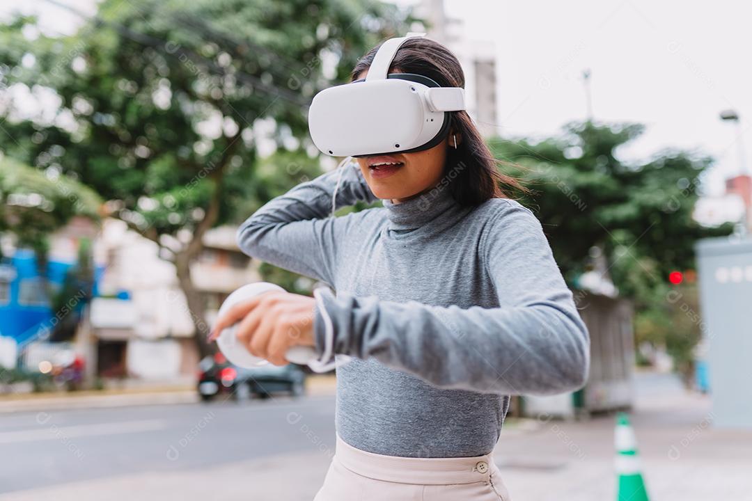 Jovem latina em pé com óculos de realidade virtual e mantenha joysticks ou dedo como uma arma.