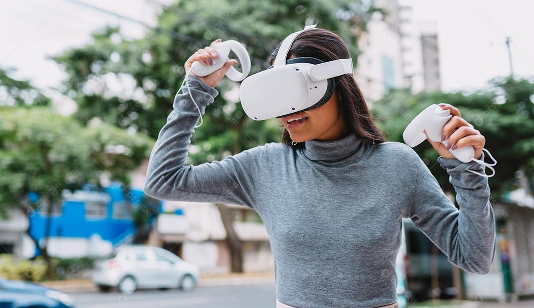 Jovem latina em pé com óculos de realidade virtual e mantenha joysticks ou dedo como uma arma.