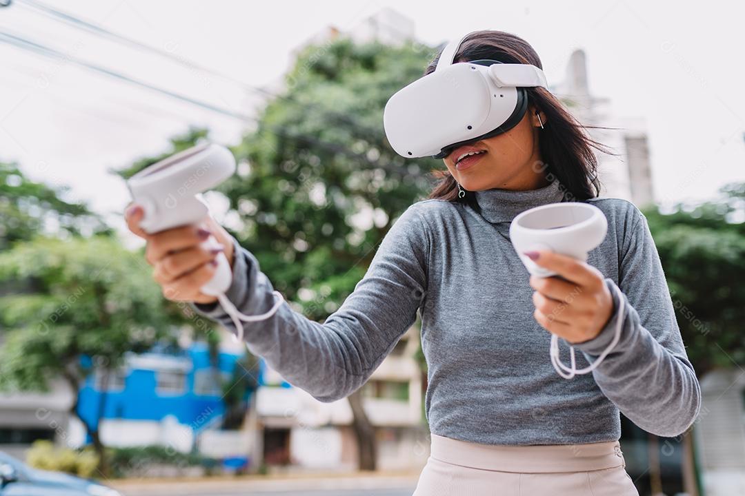 Jovem latina em pé com óculos de realidade virtual e mantenha joysticks ou dedo como uma arma.