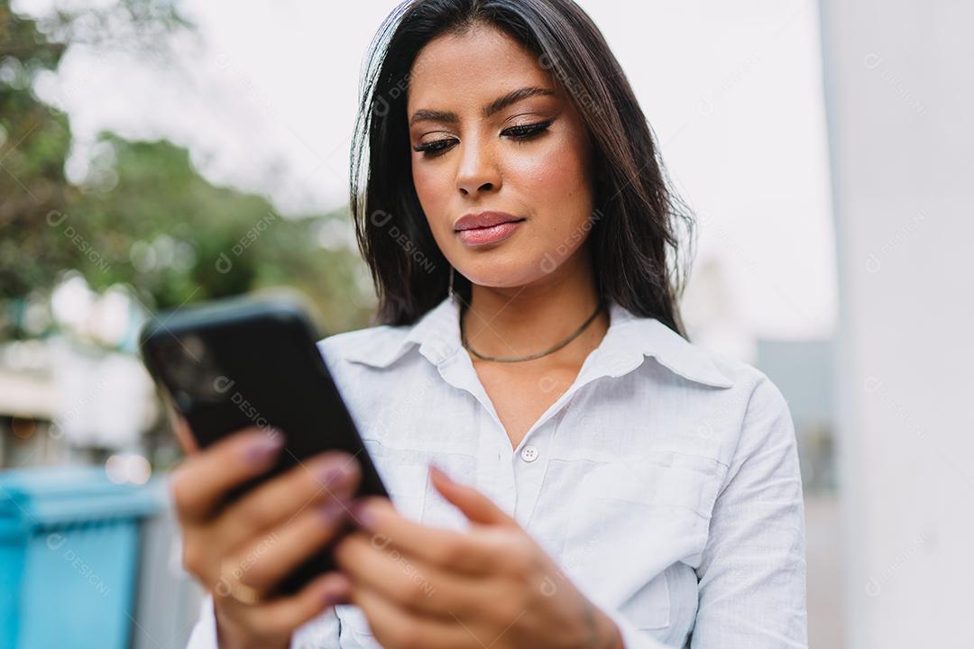Linda garota latina usando seu celular.
