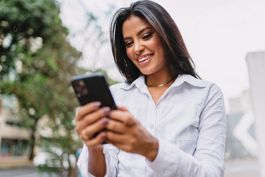 Linda garota latina usando seu celular.