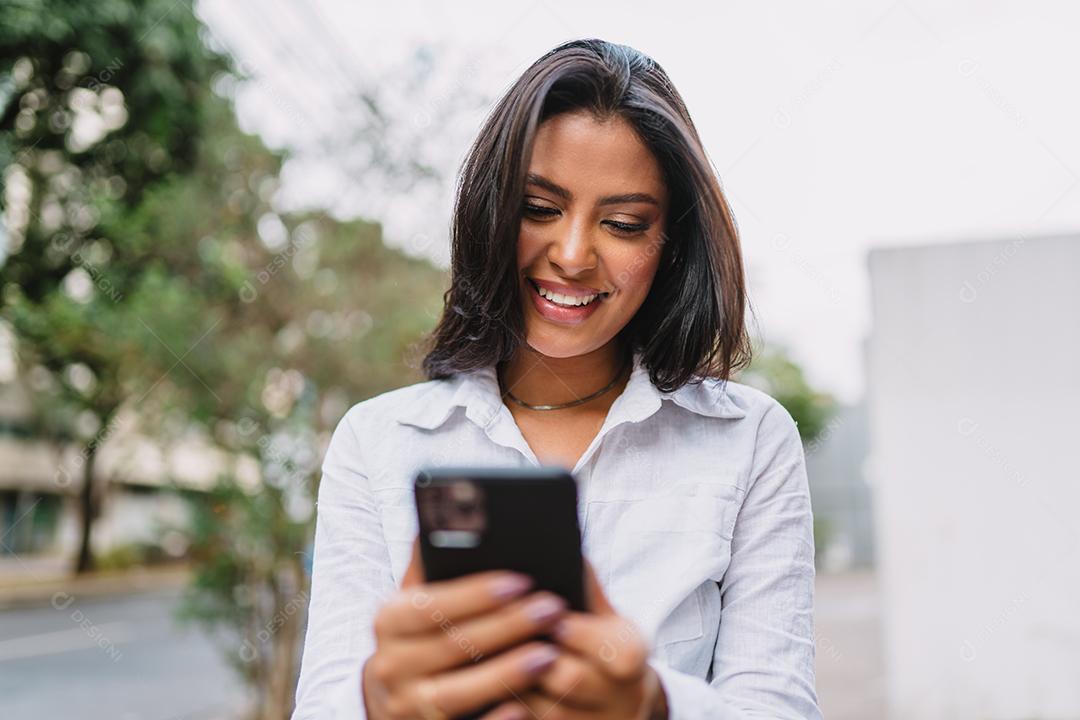 Linda garota latina usando seu celular.