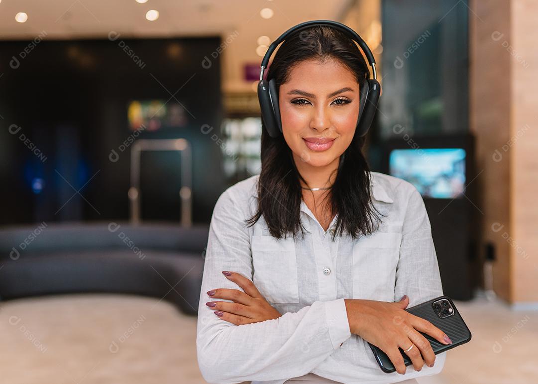 Sorrindo empresária Latina ouvindo música no lobby do hotel.