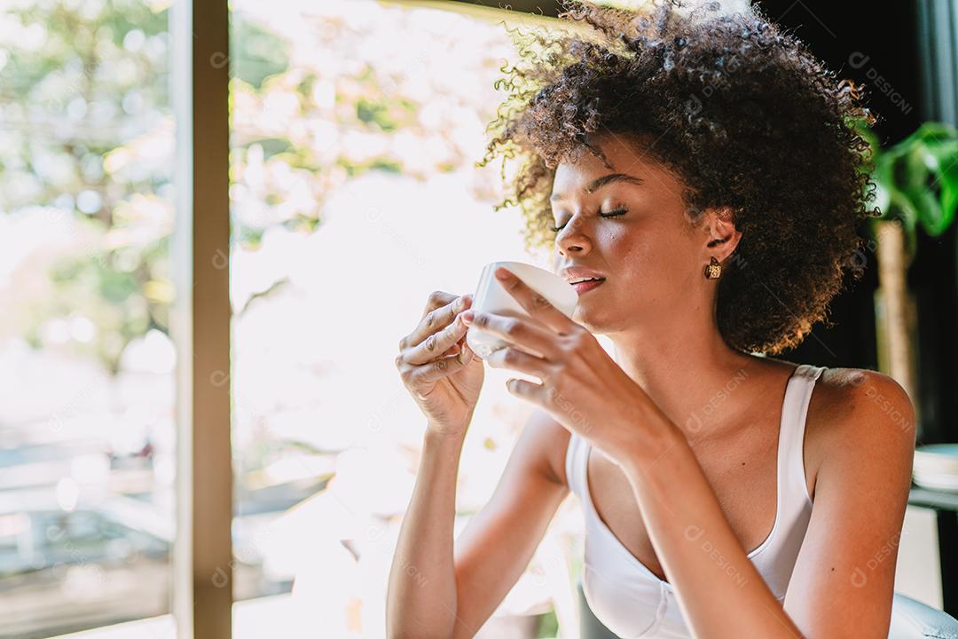 Mulher latina em um café bebendo café.