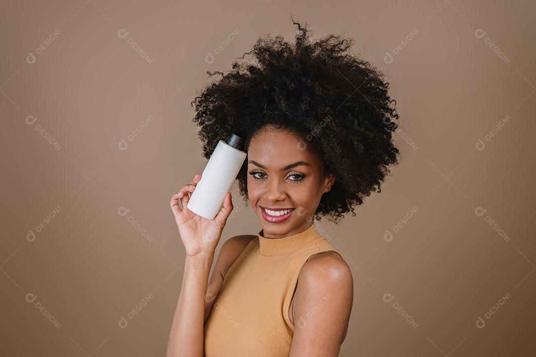 Mulher latina de beleza com penteado afro. mulher brasileira. Segurando a embalagem de xampu em branco