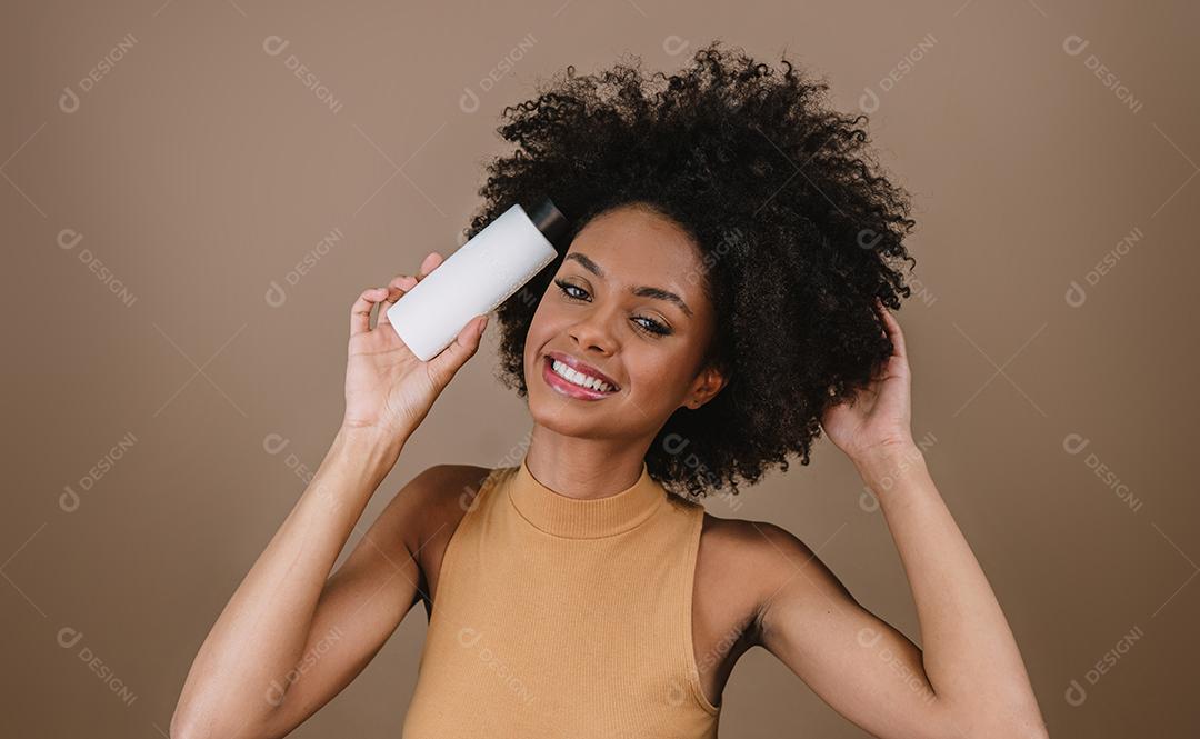 Mulher latina de beleza com penteado afro. mulher brasileira. Segurando a embalagem de xampu em branco