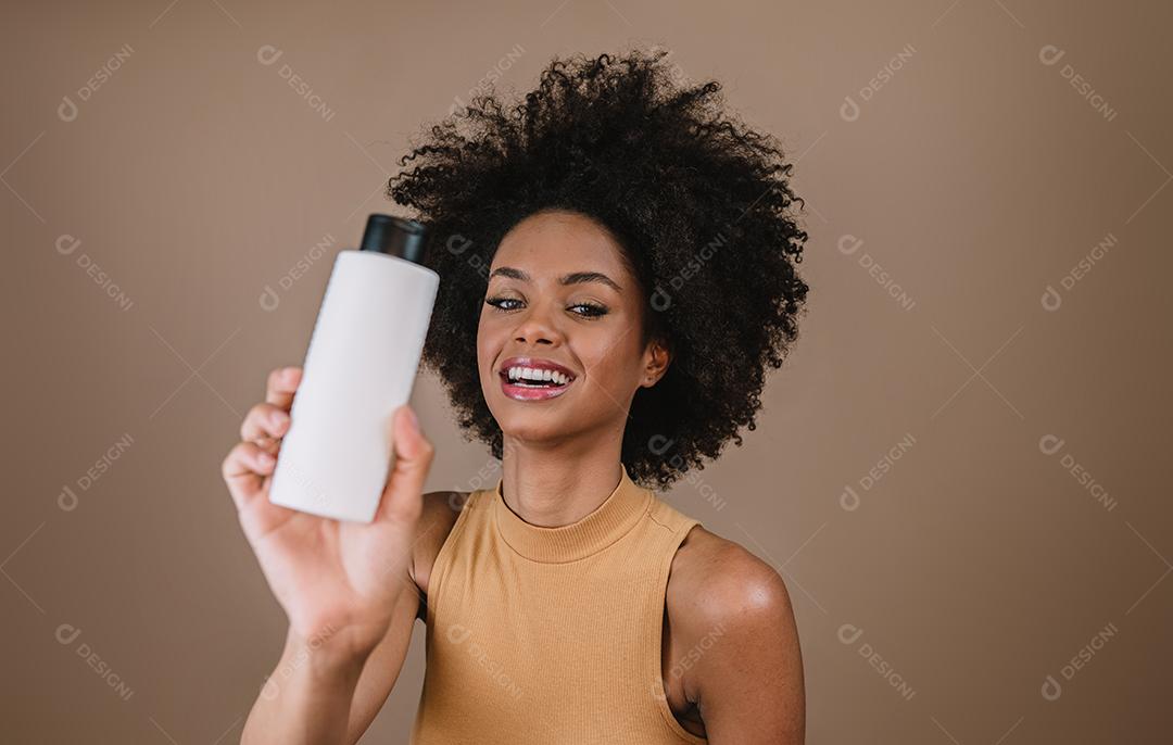 Mulher latina de beleza com penteado afro. mulher brasileira. Segurando a embalagem de xampu em branco