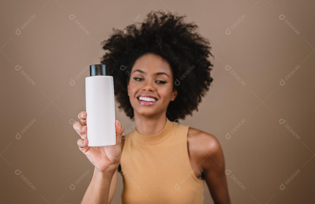 Mulher latina de beleza com penteado afro. mulher brasileira. Segurando a embalagem de xampu em branco