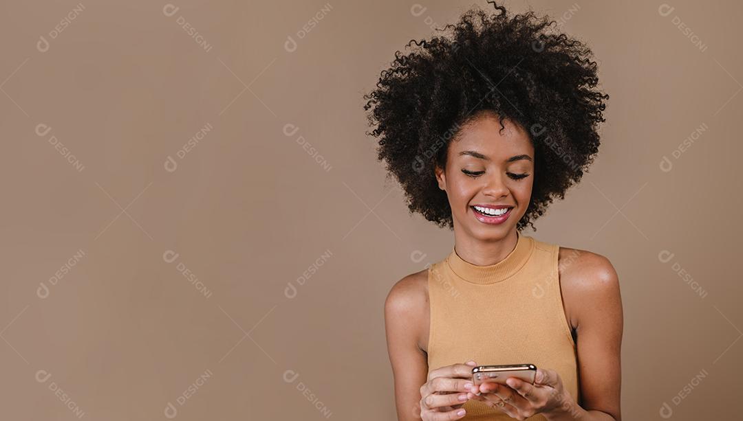 Jovem latina penteando o cabelo. Garfo para pentear cabelos cacheados. Fundo pastel.