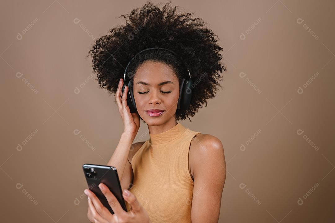 Linda garota latina usando seu celular. Ouvir música em fones de ouvido.