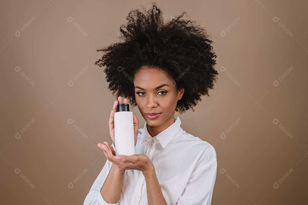 Mulher latina de beleza com penteado afro. mulher brasileira. Segurando a embalagem de xampu em branco