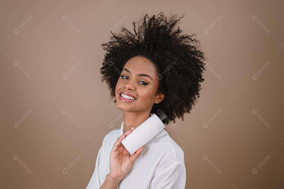 Mulher latina de beleza com penteado afro. mulher brasileira. Segurando a embalagem de xampu em branco