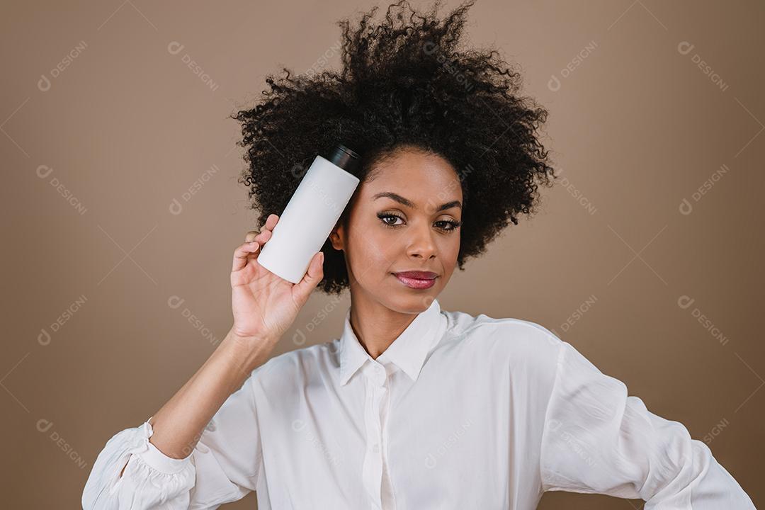 Mulher latina de beleza com penteado afro. mulher brasileira. Segurando a embalagem de xampu em branco