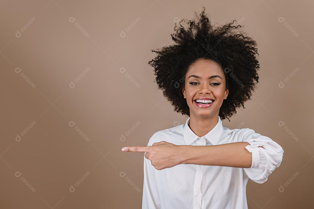 Uma jovem latina aponta para os lados. Conceito de propaganda e apresentação. Fundo pastel.