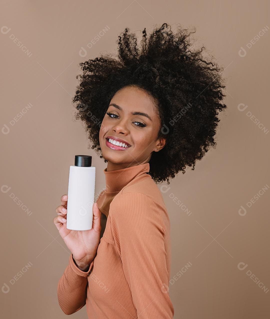 Mulher latina de beleza com penteado afro. mulher brasileira. Segurando a embalagem de xampu em branco