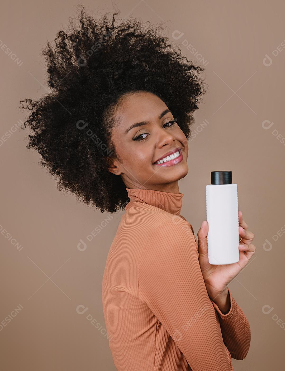 Mulher latina de beleza com penteado afro. mulher brasileira. Segurando a embalagem de xampu em branco