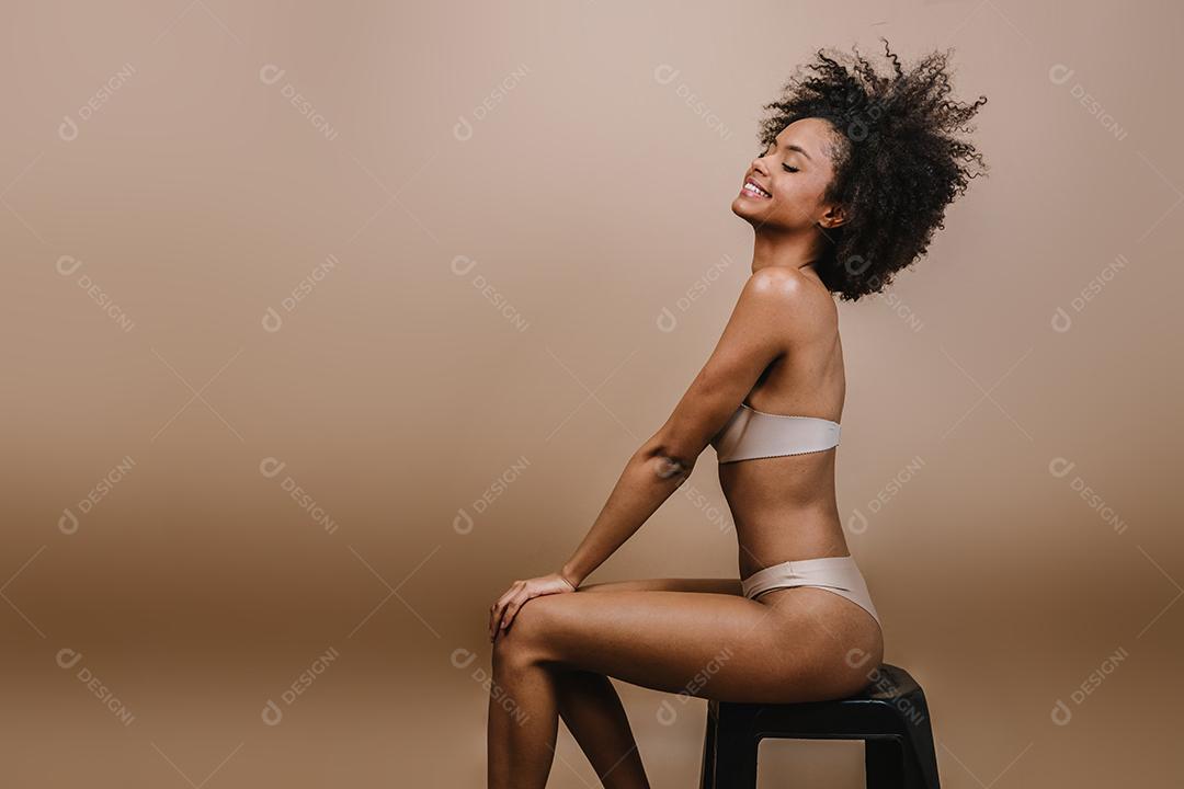 Lado uma jovem mulher afro latina sorridente. Alegria, positivo e amor. Lindo cabelo estilo africano. Fundo pastel de estúdio.