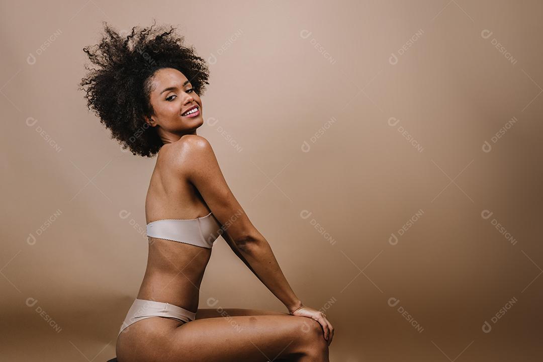 Lado uma jovem mulher afro latina sorridente. Alegria, positivo e amor. Lindo cabelo estilo africano. Fundo pastel de estúdio.