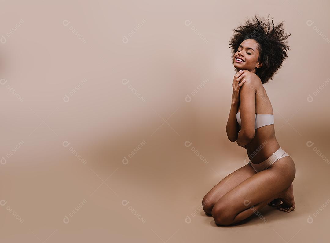 Lado uma jovem mulher afro latina sorridente. Alegria, positivo e amor. Lindo cabelo estilo africano. Fundo pastel de estúdio.