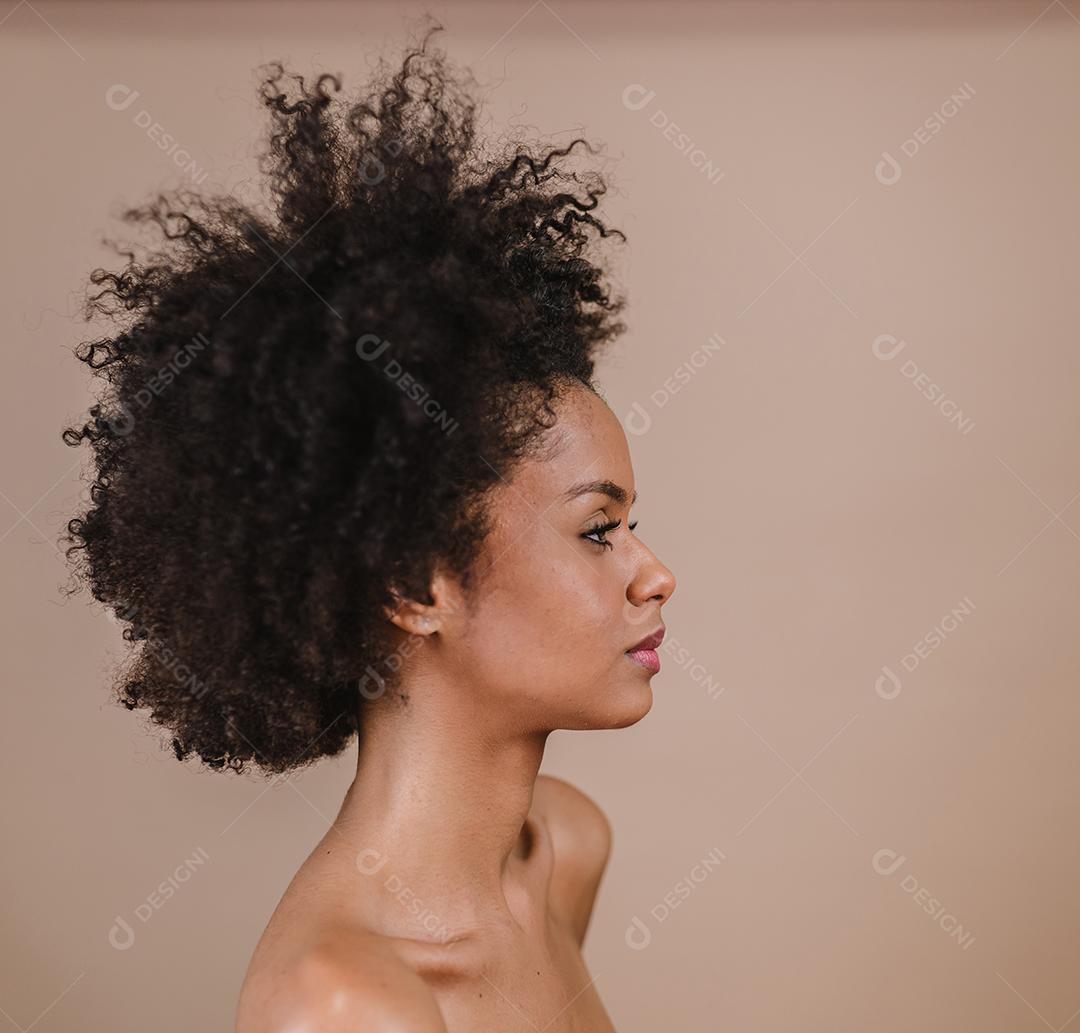 Lado uma jovem mulher afro latina sorridente. Alegria, positivo e amor. Lindo cabelo estilo africano. Fundo pastel de estúdio.