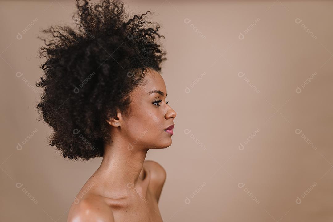 Lado uma jovem mulher afro latina sorridente. Alegria, positivo e amor. Lindo cabelo estilo africano. Fundo pastel de estúdio.