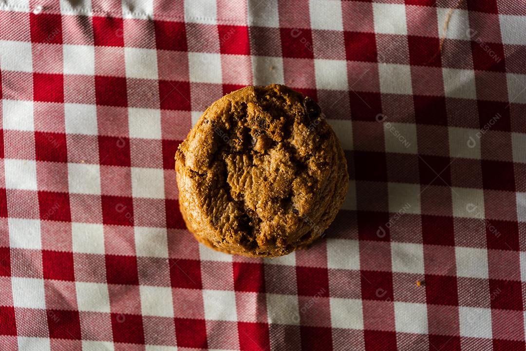 alguns biscoitos caseiros com gotas de chocolate, empilhados uns sobre os outros, na mesa de pano vermelho e fundo de madeira. conceito de café da manhã quente