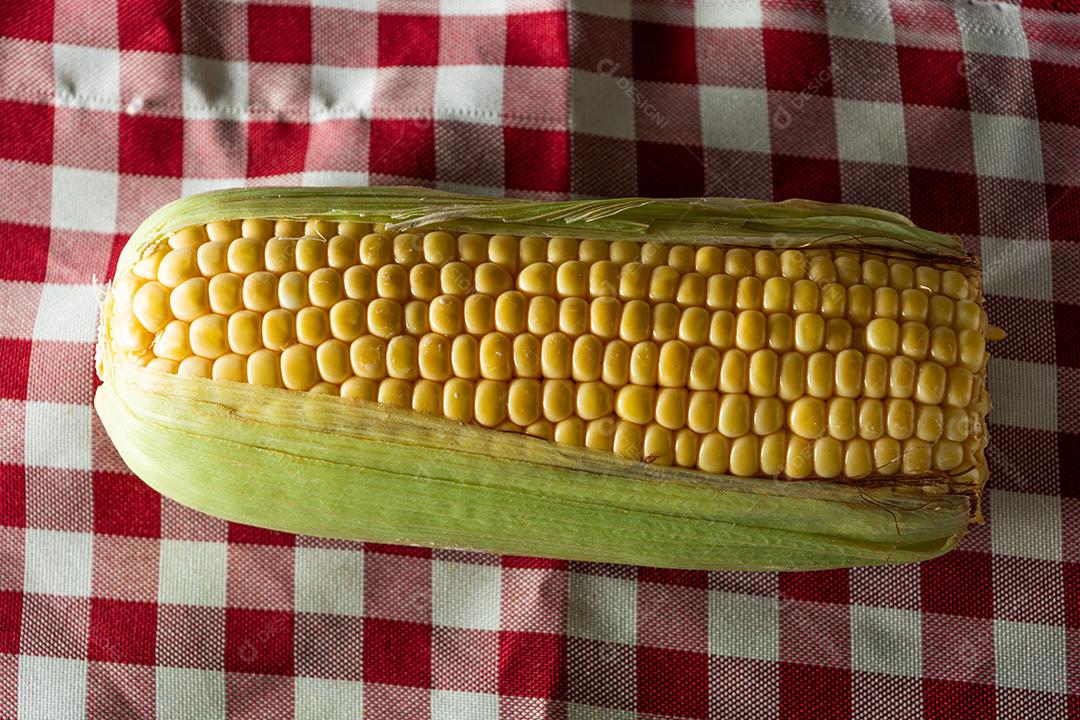 delicioso milho amarelo cru com folha verde e espiga, sobre canudos secos e superfície de madeira