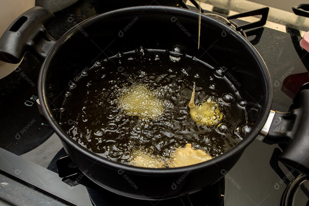 fritar a massa no óleo, para uma receita típica brasileira chamada bolinho de chuva